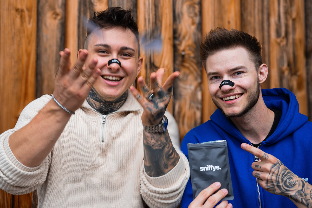 Die sniffys. Gründer Phil und Robin lachend mit Nasenstreifen und Packung